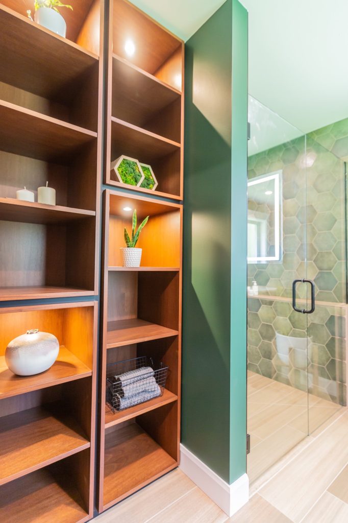 Custom wooden shelving with decorative items and plants, adjacent to a modern bathroom with hexagonal tiles and a glass shower, illustrating DMC Contracting's focus on tailored home design in Abbotsford.
