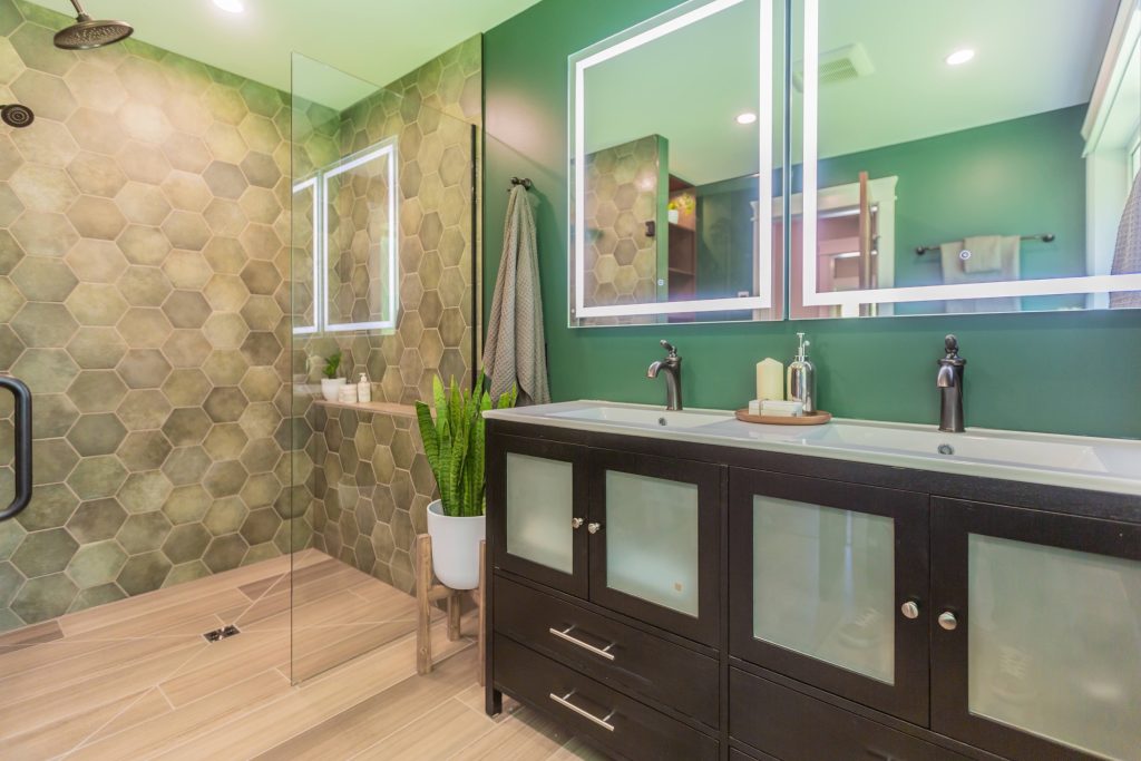 Modern bathroom renovation featuring hexagonal tile walls, dual sink vanity with black cabinetry, sleek mirrors, and greenery, emphasizing DMC Contracting's design expertise for Fraser Valley homeowners.