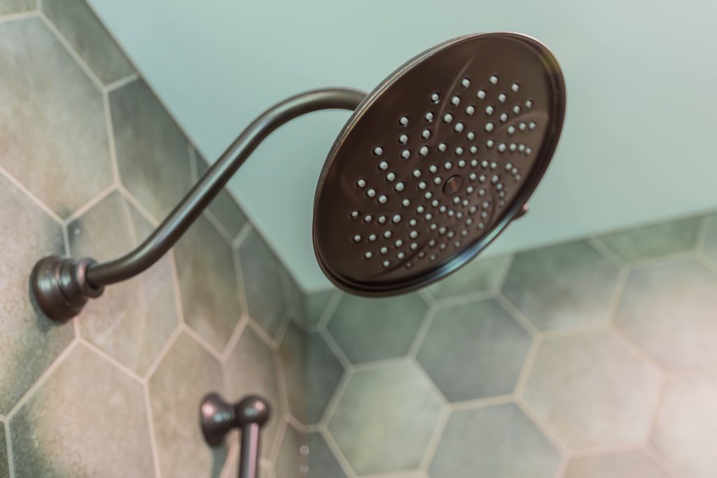 Showerhead with modern design and hexagonal tile background, highlighting features for future-proofing multigenerational homes.