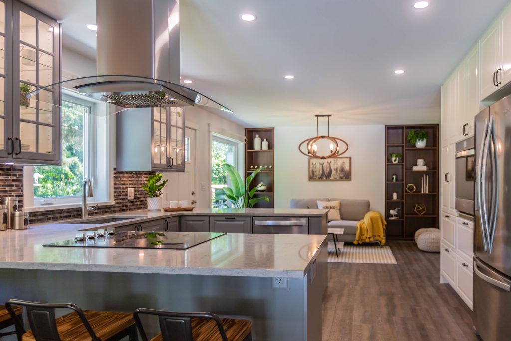 Modern kitchen renovation featuring gray cabinetry, stainless steel appliances, and an open layout with a cozy seating area, emphasizing functionality and contemporary design.