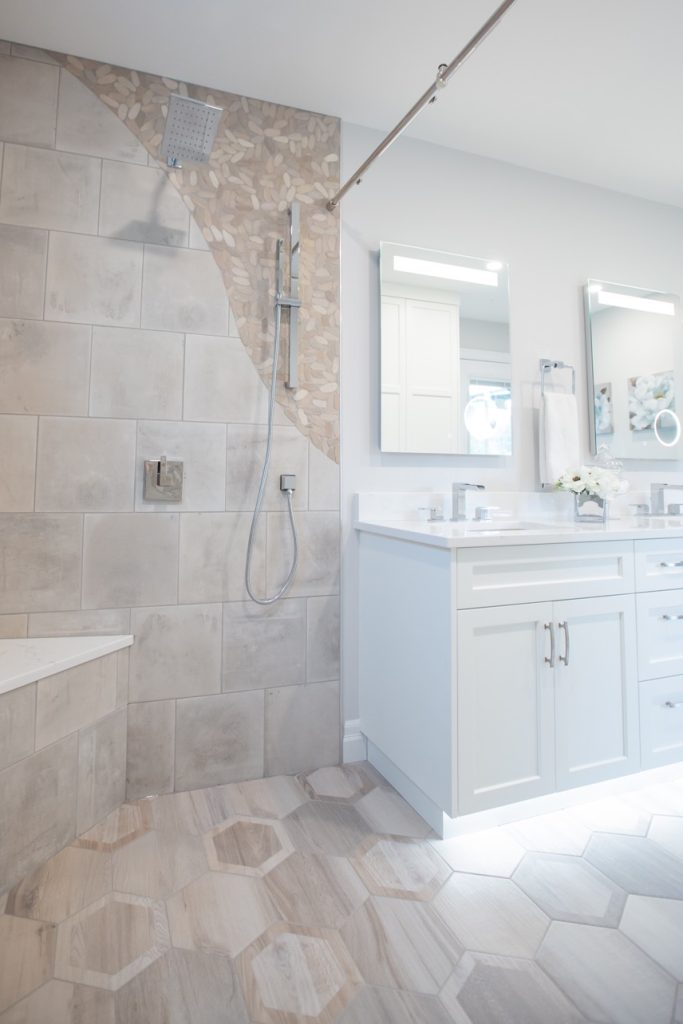 Modern bathroom renovation featuring a walk-in shower with a rainfall showerhead, textured tile wall, and a sleek vanity with dual sinks, emphasizing functionality and style in home renovations.