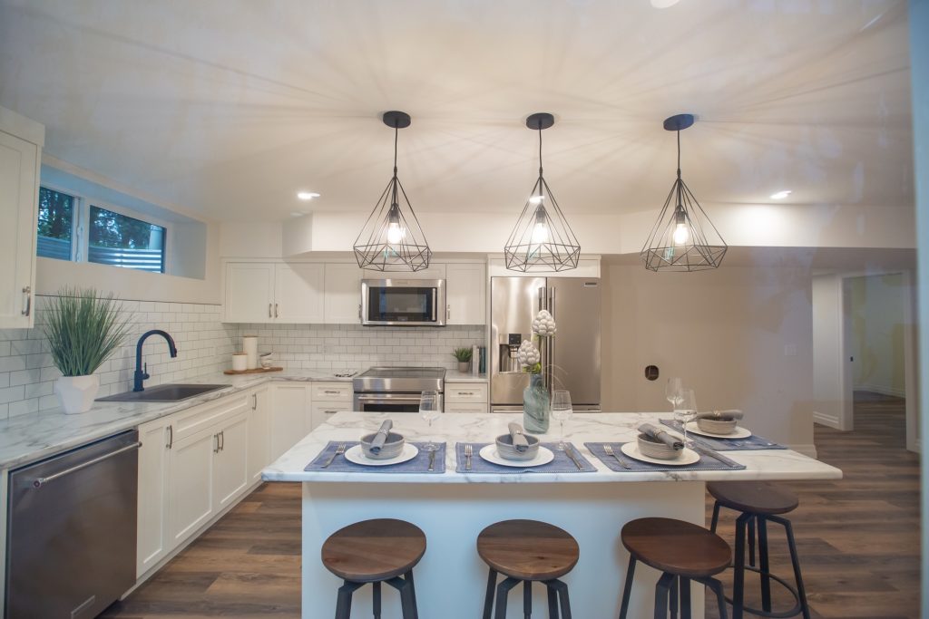 Modern kitchen design featuring white cabinetry, marble countertops, stainless steel appliances, and stylish pendant lighting, with a dining area set for guests, emphasizing efficient layout and inviting ambiance for family gatherings.