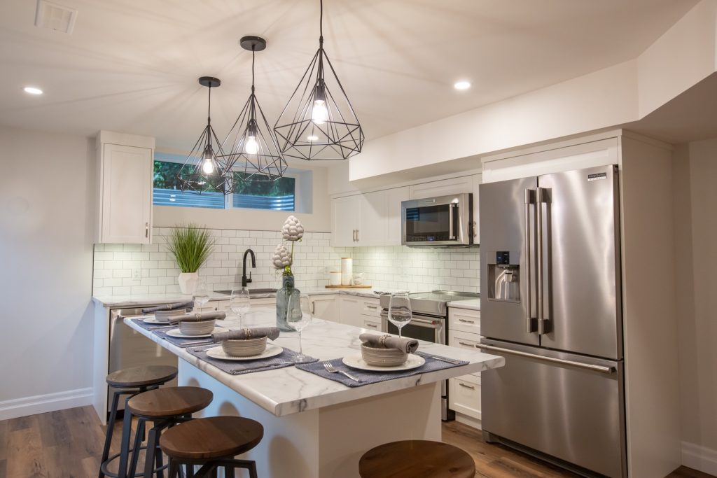 Modern kitchen featuring elegant marble countertops, stylish pendant lighting, and high-end appliances, designed for luxury home renovations in Langley and Abbotsford.