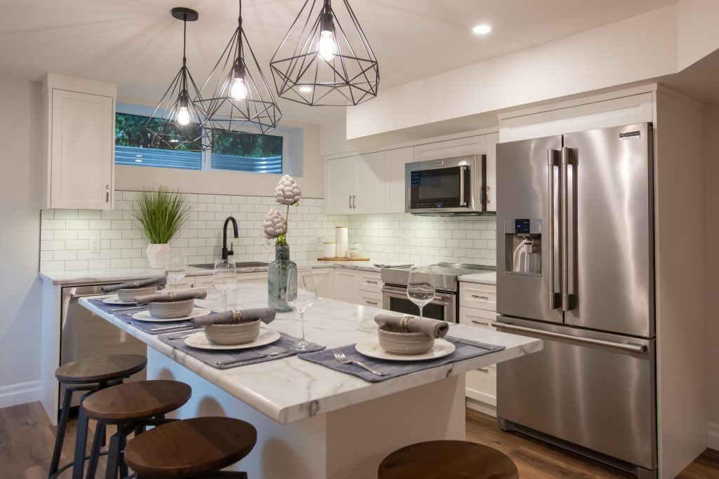 Modern kitchen renovation featuring a sleek marble island, stylish pendant lighting, stainless steel appliances, and an open layout designed for functionality and comfort.