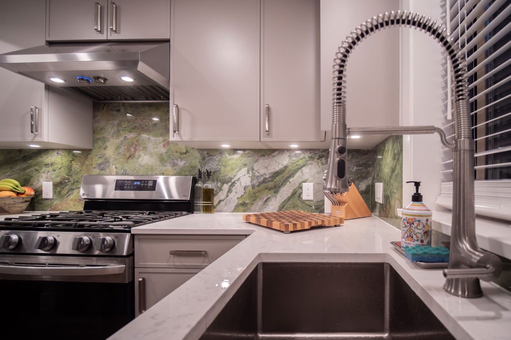 Modern kitchen with stainless steel appliances, sleek cabinetry, and a marble countertop, featuring a stylish faucet and decorative elements, emphasizing functional and beautiful design for home renovations.