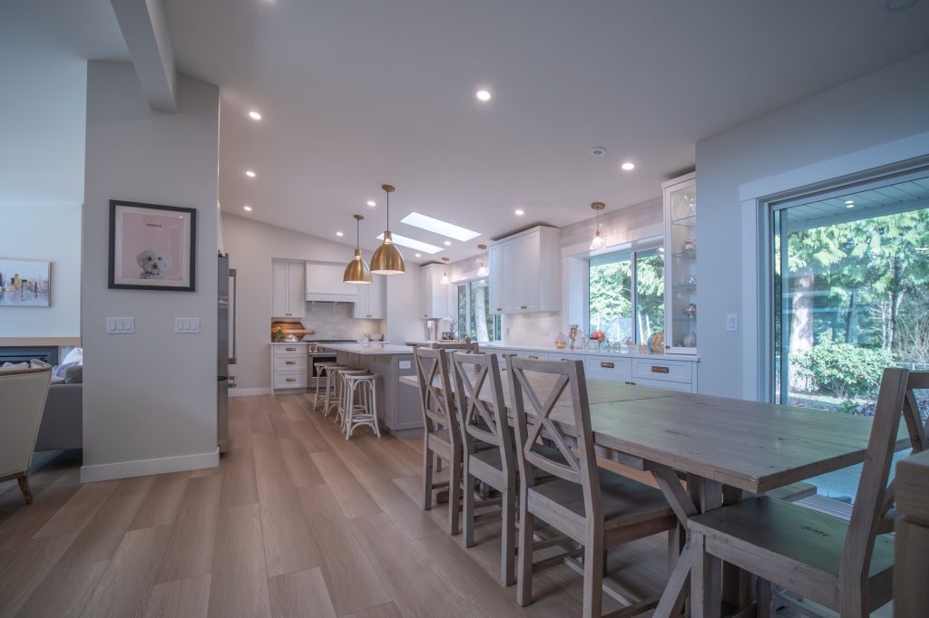 Modern kitchen interior with open layout, featuring wooden dining table, stylish cabinetry, and pendant lighting, highlighting renovation potential for improved living spaces in Abbotsford.