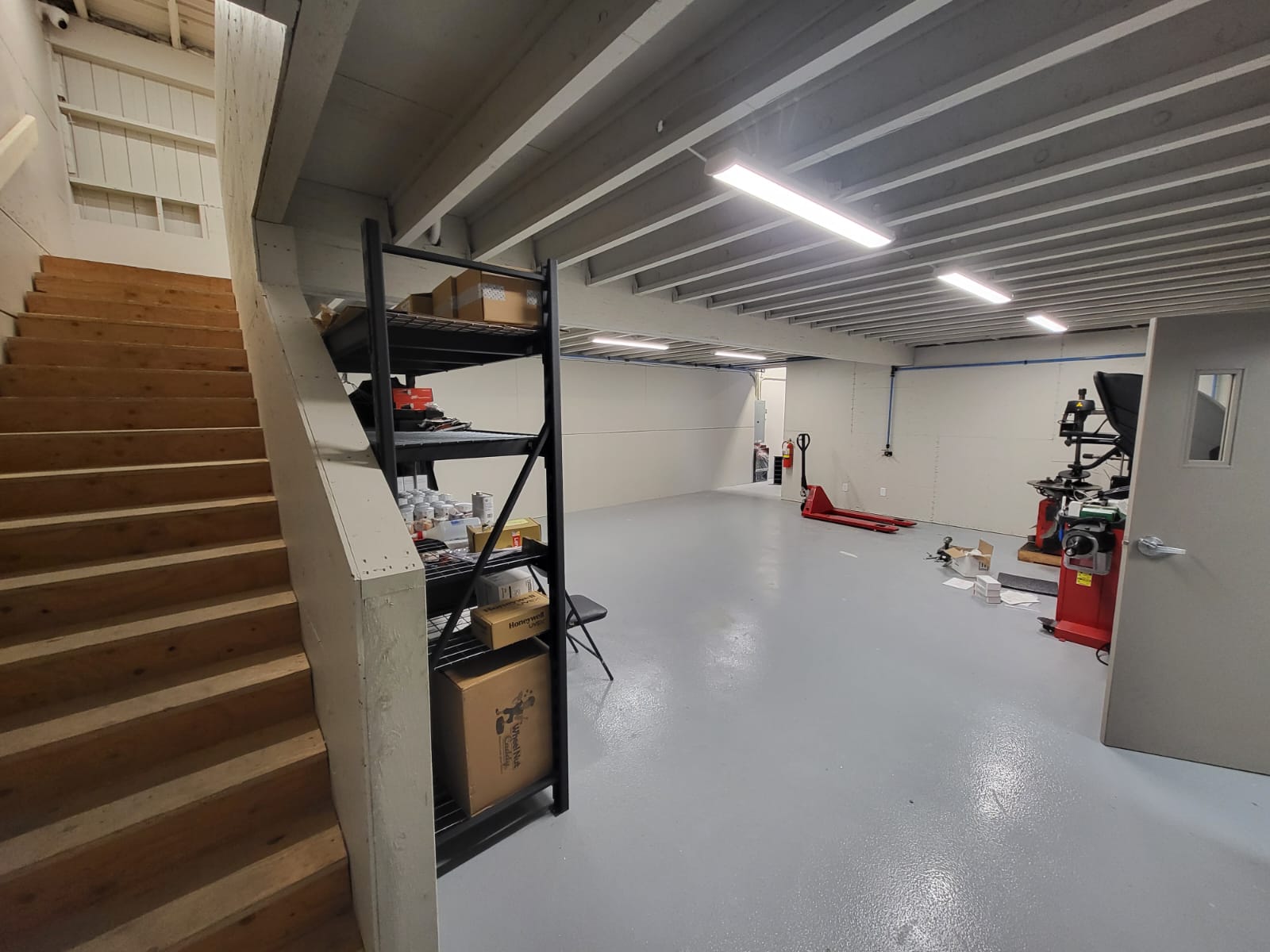 Professional office construction interior with wooden stairs, shelving unit, and equipment, showcasing a spacious and functional workspace for business operations.